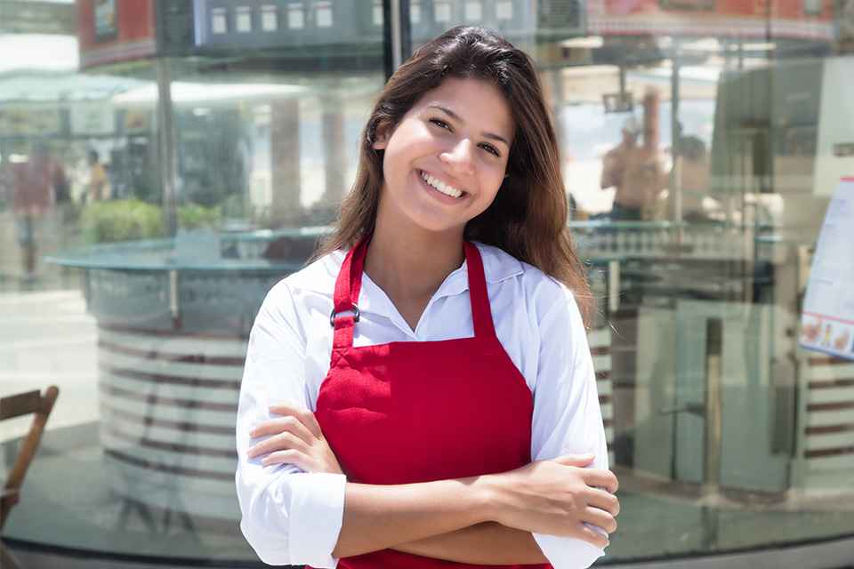 Foto: Junge Kellnerin vor dem Restaurant